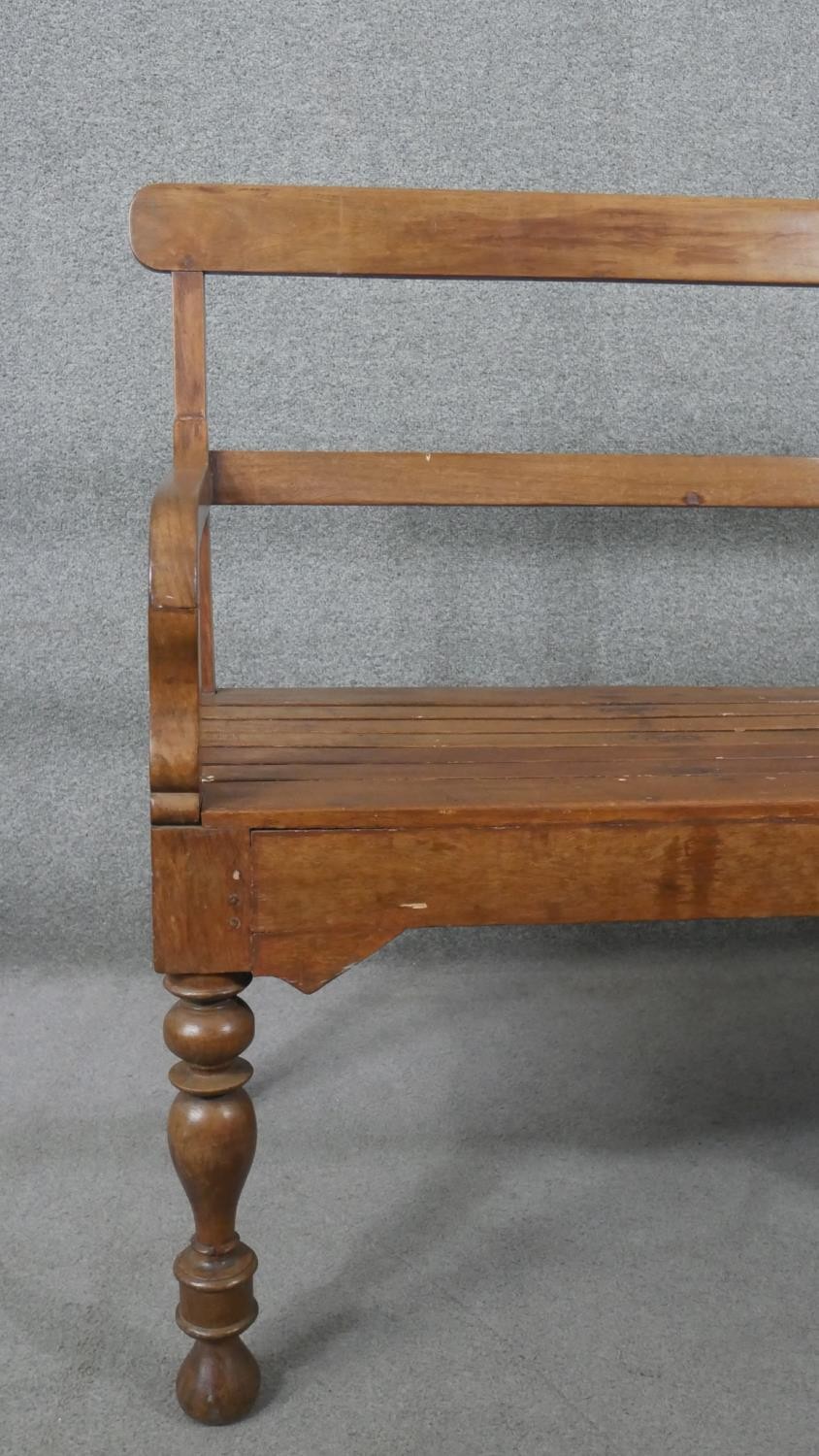 An Indian teak bench, with a bar back and open arms, over a slatted seat, on turned legs. H.93 W.165 - Image 5 of 6