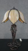 A table lamp with leaded floral form opaque glass shade on a naturalistic scrolling metal base. H.55