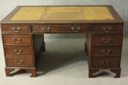 A 20th century mahogany pedestal desk, with a tooled green leather skiver, over an arrangement of