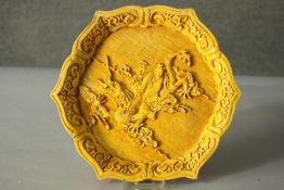 A Japanese carved yellow resin and lacquered hexagonal plate depicting an immortal riding a