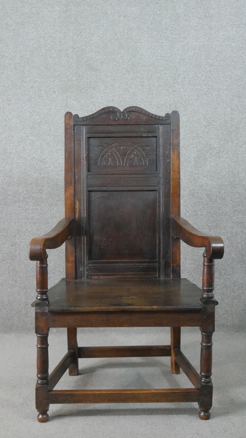 A late 19th century oak wainscot armchair, the panelled back with scrolling top rail, over open