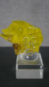 A art glass figure of a head with flowing yellow hair mounted on a clear glass block. H.19 W.8.5 D.