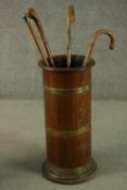 A vintage brass bound oak umbrella stand with a collection of four walking sticks. H.66 Dia.30cm.
