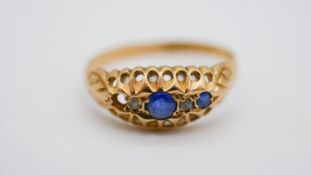 An 18 carat yellow gold sapphire and diamond gypsy ring, set with two round mixed cut sapphires