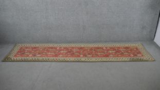 A Kazak Motif Runner with repeating stylised motifs on a salmon pink ground within multiple borders.