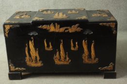 A 20th century Chinese camphorwood trunk, ebonised, carved with sailing boats in relief, with a