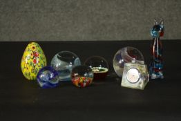 A collection of art glass paperweights, including a yellow Millefiori egg paperweight, a floral