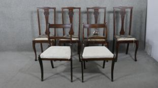 A harlequin set of six dining chairs, including a set of four with a roundel carved to the back