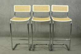 Manner of Marcel Breuer, a set of three 1970's bar stools, with caned back and seat, on a tubular