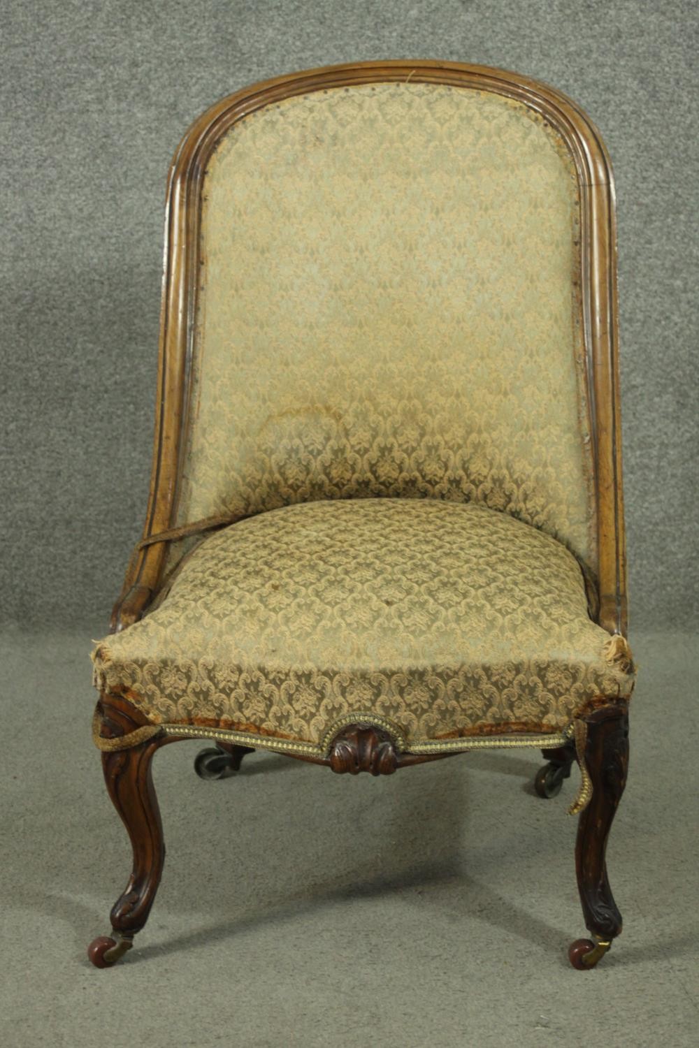 A Victorian walnut nursing chair, upholstered in green fabric, on carved cabriole legs.