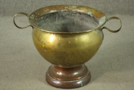 A 19th century twin handled brass pot on a copper circular stepped base. H.35 Dia.58cm.