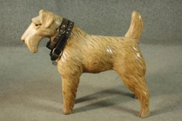 A carved and painted figure of a standing terrier. H.56 W.64 D.20cm.