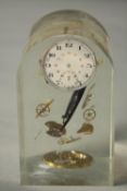 A deconstructed clock parts clear acrylic paperweight. H.13 W.8 D.8cm.