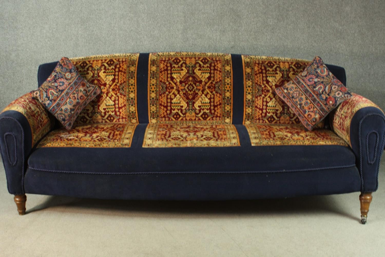 A late Victorian sofa, upholstered in blue velour, with sections of a Persian Sarouk rug to the
