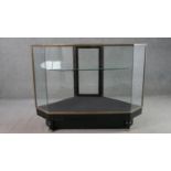 A mid 20th century shop corner display cabinet, glazed, with brass edges, enclosing a single