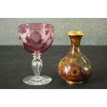 A cranberry glass etched vine design goblet along with a gilded brass Japanese cloisonné vase
