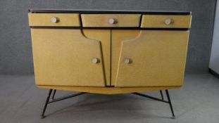 A circa 1950s sideboard, with a white formica top, covered in yellow fabric, with three short
