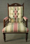 An Edwardian walnut open armchair, upholstered in striped fabric, with a studded back, on turned