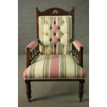 An Edwardian walnut open armchair, upholstered in striped fabric, with a studded back, on turned