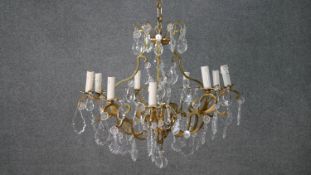 A vintage nine branch chandelier with scrolling gilt metal frame and cut crystal drops. H.50 W.60cm