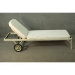 A white painted cast iron garden lounger, with white upholstered cushions, the faux bamboo frame