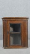A late Victorian oak corner cabinet, with a glazed door enclosing a shelf. H.69 W.60 D.36cm