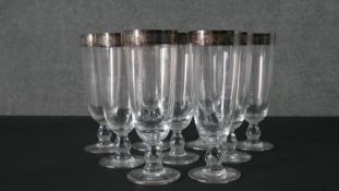 A set of nine champagne flutes with etched silvered rims retailed by Mulberry. H.18.5 Diam.7cm