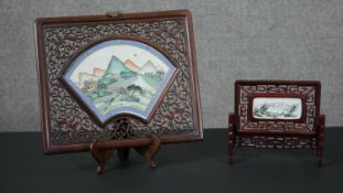A carved Chinese rosewood panel, set with a fan shaped famille rose porcelain insert depicting a