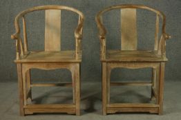 A pair of Chinese teak horseshoe back armchairs, with a plain splat back, the legs joined by