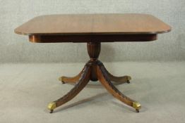 A George III style mahogany extending dining table, with four leaves, on a quatraform base