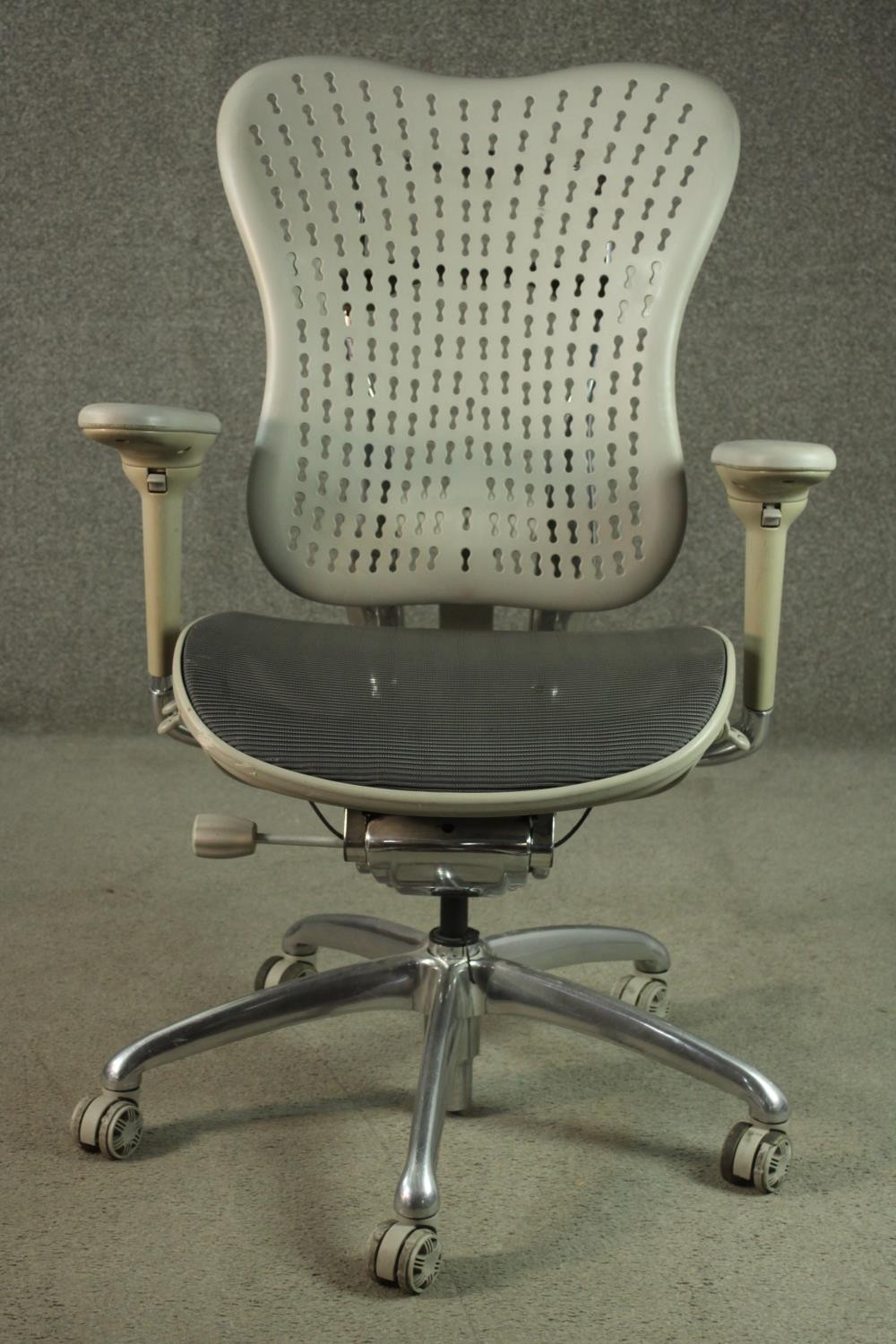 A Formway style office chair, in grey, with a pierced back, and adjustable arms, on a five point