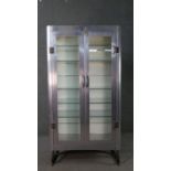 A mid 20th century steel medical cabinet, in the manner of Airstream, with two glazed doors, and