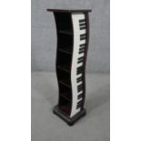 A painted CD rack in the form of a piano with black and white key detailing. H.95 W.24 D.21cm