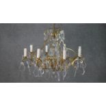 A vintage eight branch chandelier with scrolling gilt metal frame and cut crystal drops. H.47 W.60cm