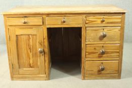 A Victorian pitch pine kneehole desk, with three short drawers, over a cupboard door to one