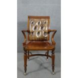 A Victorian mahogany library or desk chair, with a buttoned brown leather back, over outswept oven