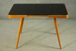 A mid 20th century Czech coffee table, with a black glass top, on tapering cylindrical legs, with