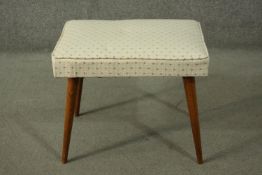 A circa 1960's teak stool, the seat upholstered in patterned white fabric, hinged, on tapering legs.