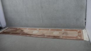 A Chinese woollen runner with character mark motifs on a mink ground. L.353 W.70cm