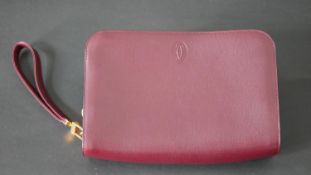 A leather Cartier clutch bag with red silk interior with Cartier writing and raised Cartier monogram