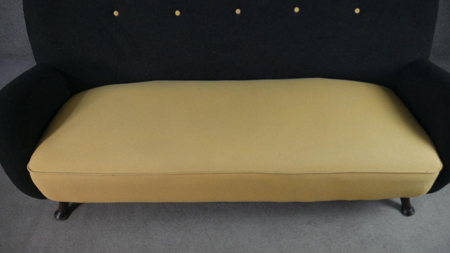 A circa 1950s two seater sofa,, the buttoned back upholstered in black fabric, over a yellow - Image 2 of 6