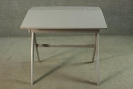 A mid 20th century grey painted school desk, with a foldover top. H.71 W.75 D.56cm.