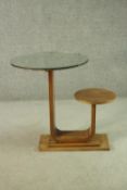 An Art Deco teak table and stool, with a circular glass table top, on a support which curves up to a