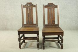 A pair of 19th century country oak dining chairs, the back carved with a flowerhead, over solid