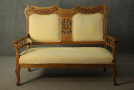 An Arts & Crafts fruitwood two seater sofa, the back rail carved with oak leaves and acorns,