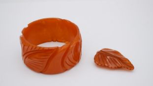 An Art Deco carved amber bakelite leaf design bangle and matching leaf scarf clip.