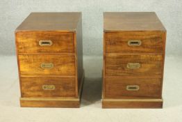 A pair of campaign style camphorwood bedside chests, brass corners, with three drawers having