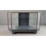 A mid 20th century shop corner display cabinet, glazed, with brass edges, enclosing a single