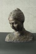 A bronze effect resin and concrete bust of a young female with hair in a bun, unsigned. H.48 W.43cm.