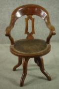 An Edwardian walnut swivel desk chair, with a curved back and pierced splat, over a circular leather